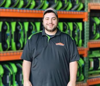 Phillip is a production technician, he is standing in front of a shelving unit of green air movers